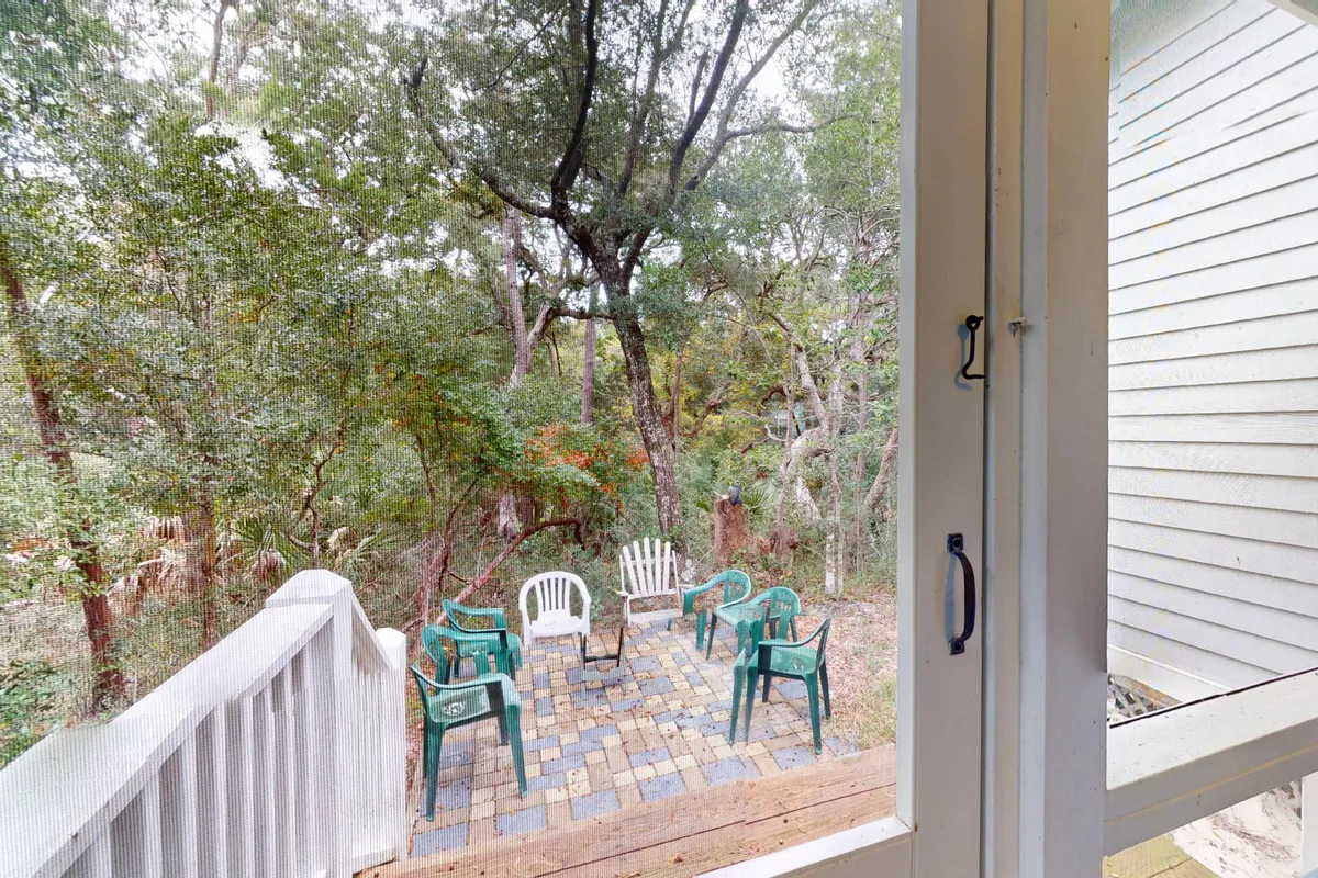 An exterior view of a serene backyard with a fire pit surrounded by a seating area and mature trees. The space is designed for outdoor gatherings, relaxation, evening bonfires, or enjoying coffee while immersed in nature.