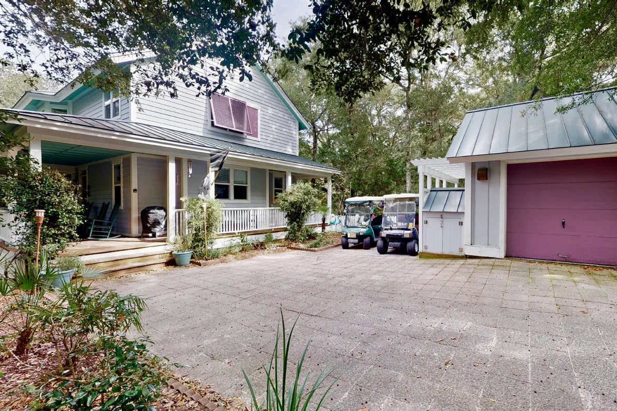This exterior shot showcases the cottage's front porch along with multiple golf carts parked in front, set against a relaxed and welcoming backdrop. The image captures the heart of the home as a launch point for daily adventures, with easy access to the island's many activities.