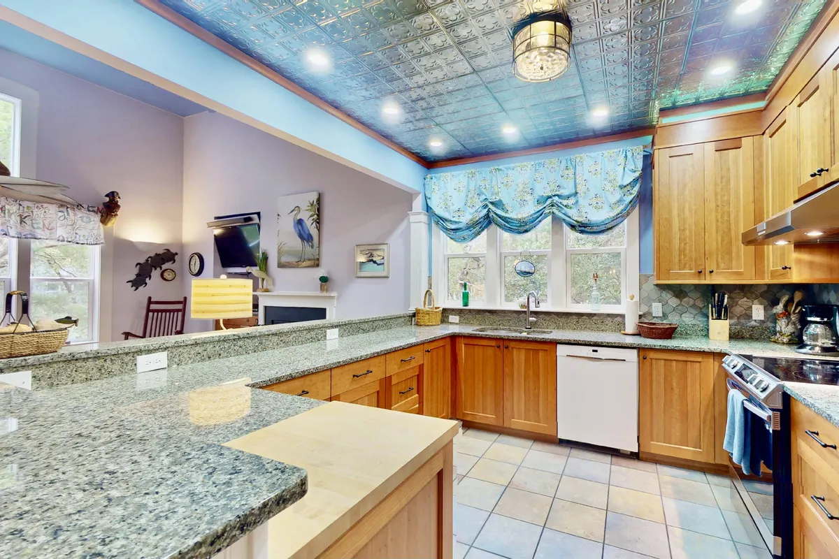 A cheerful kitchen scene centered around granite countertops, colorful window treatments, and modern kitchen appliances. The kitchen features ample space for cooking and gathering, with playful decor and a welcoming, family-friendly vibe. Sunlight streams in, enhancing the inviting atmosphere.
